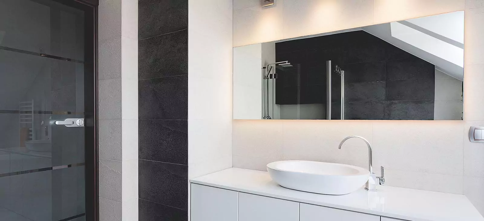 Illuminated mirror is installed on a white wall with a single sink in the aesthetic bathroom.